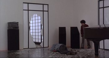Movie still from “The Punisher” (1989), directed by Mark Goldblatt – A person laying on the ground in front of a window; Wide shot, Low angle