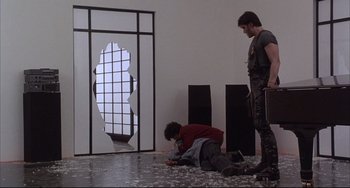 Movie still from “The Punisher” (1989), directed by Mark Goldblatt – Two men are standing in front of a broken glass window; Wide shot, Low angle