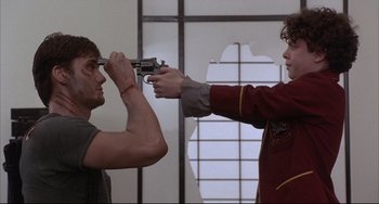 Movie still from “The Punisher” (1989), directed by Mark Goldblatt – Two men are holding guns in a room; Medium shot, Over the shoulder angle