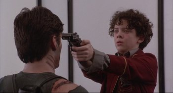 Movie still from “The Punisher” (1989), directed by Mark Goldblatt – A young man holding a gun up to his face; Close Up shot, Over the shoulder angle