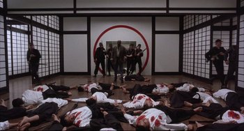 Movie still from “The Punisher” (1989), directed by Mark Goldblatt – A group of men standing in front of a group of dead bodies; Wide shot, High angle