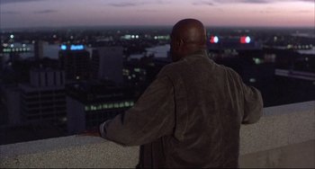 Movie still from “The Punisher” (1989), directed by Mark Goldblatt – A man standing on a ledge looking out over a city at night; Wide shot, Low angle