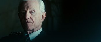 Movie still from “The Purge: Election Year” (2016), directed by James DeMonaco – An older man wearing a suit and tie; Close Up shot, Over the shoulder angle