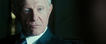Movie still from “The Purge: Election Year” (2016), directed by James DeMonaco – An older man wearing a suit and white shirt; Close Up shot, Over the shoulder angle