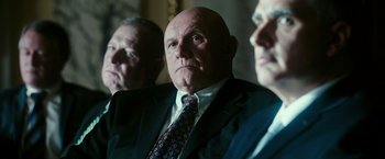 Movie still from “The Purge: Election Year” (2016), directed by James DeMonaco – A man in a suit and a tie looking at the camera; Medium shot, Low angle