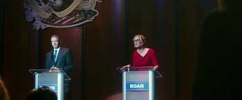 Movie still from “The Purge: Election Year” (2016), directed by James DeMonaco – A woman standing at a podium in front of a microphone; Wide shot, Low angle