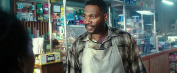 Movie still from “The Purge: Election Year” (2016), directed by James DeMonaco – A man wearing an apron standing in front of a display case; Medium shot, Over the shoulder angle