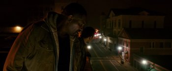Movie still from “The Purge: Election Year” (2016), directed by James DeMonaco – A man standing next to another man on the side of the street; Medium shot, Low angle