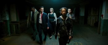Movie still from “The Purge: Election Year” (2016), directed by James DeMonaco – A group of people are walking in a dark room; Wide shot, High angle