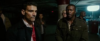 Movie still from “The Purge: Election Year” (2016), directed by James DeMonaco – A group of people standing around in a building; Medium shot, Over the shoulder angle