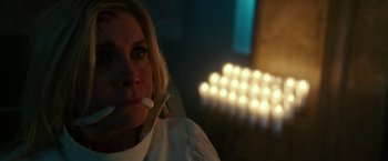 Movie still from “The Purge: Election Year” (2016), directed by James DeMonaco – A woman sitting in front of a row of lit candles; Close Up shot, Low angle