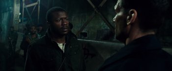 Movie still from “The Purge: Election Year” (2016), directed by James DeMonaco – A man in a green jacket talking to another man in a black jacket; Close Up shot, Over the shoulder angle