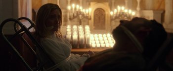 Movie still from “The Purge: Election Year” (2016), directed by James DeMonaco – A woman sitting in front of candles in a church; Medium shot, Over the shoulder angle