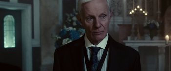 Movie still from “The Purge: Election Year” (2016), directed by James DeMonaco – An older man wearing a suit and tie; Close Up shot, Over the shoulder angle