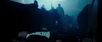 Movie still from “The Purge: Election Year” (2016), directed by James DeMonaco – A crowd of people sitting in a dark room at night; Wide shot, Low angle