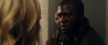 Movie still from “The Purge: Election Year” (2016), directed by James DeMonaco – A person in a room near a brick wall; Close Up shot, Over the shoulder angle