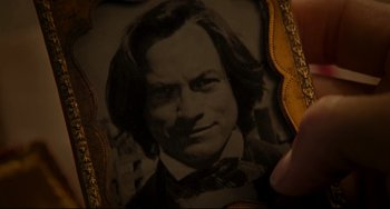 Movie still from “The Quick and the Dead” (1995), directed by Sam Raimi – A picture of a man with long hair and wearing a bow tie; Extreme Close Up shot, High angle