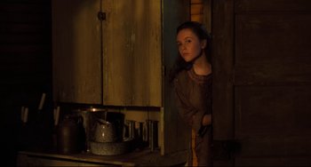 Movie still from “The Quick and the Dead” (1995), directed by Sam Raimi – A young woman standing in a kitchen next to a stove; Medium shot, Low angle