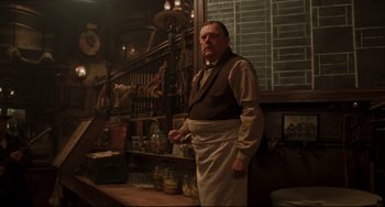 Movie still from “The Quick and the Dead” (1995), directed by Sam Raimi – A man standing in front of a counter in a restaurant; Medium shot, Low angle