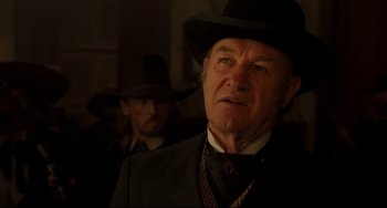 Movie still from “The Quick and the Dead” (1995), directed by Sam Raimi – A man in a suit and hat standing next to another man in a hat; Close Up shot, Over the shoulder angle