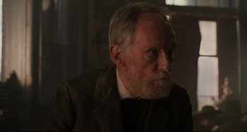 Movie still from “The Quick and the Dead” (1995), directed by Sam Raimi – An older man with a beard and a suit; Close Up shot, Over the shoulder angle
