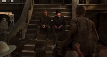 Movie still from “The Quick and the Dead” (1995), directed by Sam Raimi – Two men sitting on the steps of a building; Wide shot, High angle