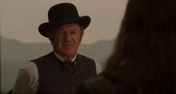 Movie still from “The Quick and the Dead” (1995), directed by Sam Raimi – An older man wearing a black hat and a vest; Close Up shot, Over the shoulder angle