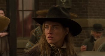 Movie still from “The Quick and the Dead” (1995), directed by Sam Raimi – A woman wearing a cowboy hat in a room with a brick wall; Close Up shot, Over the shoulder angle
