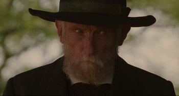 Movie still from “The Quick and the Dead” (1995), directed by Sam Raimi – An old man with a beard wearing a hat; Close Up shot, Low angle