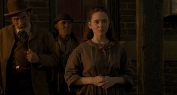 Movie still from “The Quick and the Dead” (1995), directed by Sam Raimi – A woman standing in front of a man in a hat; Medium shot, Over the shoulder angle