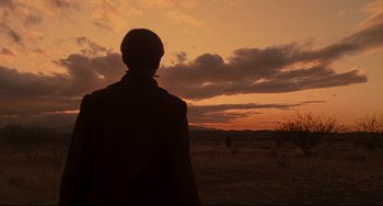 Movie still from “The Quick and the Dead” (1995), directed by Sam Raimi – A man standing in a field looking at the sunset; Wide shot, Low angle