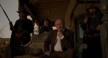Movie still from “The Quick and the Dead” (1995), directed by Sam Raimi – A man in a suit and hat sitting next to another man in a hat; Medium shot, Low angle