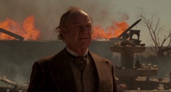 Movie still from “The Quick and the Dead” (1995), directed by Sam Raimi – An older man in a suit and tie standing in front of a fire; Close Up shot, Low angle