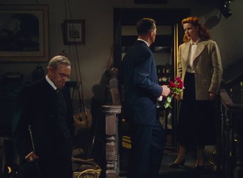 Movie still from “The Quiet Man” (1952), directed by John Ford – A group of people standing in a living room; Medium shot, High angle