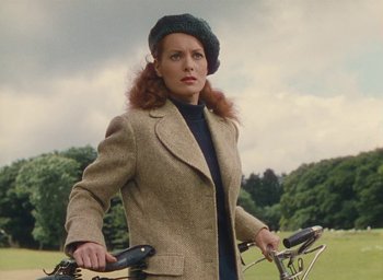 Movie still from “The Quiet Man” (1952), directed by John Ford – A woman in a brown jacket and a green hat riding a bike; Medium shot, Low angle