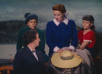 Movie still from “The Quiet Man” (1952), directed by John Ford – A group of people standing around a woman holding a hat; Medium shot, Low angle