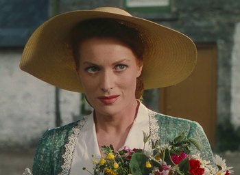Movie still from “The Quiet Man” (1952), directed by John Ford – A woman in a hat holding a bouquet of flowers; Close Up shot, Over the shoulder angle