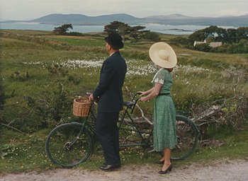 Movie still from “The Quiet Man” (1952), directed by John Ford – A man and a woman standing next to a bicycle; Wide shot, High angle