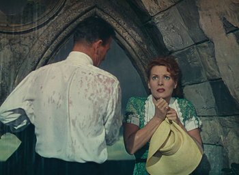 Movie still from “The Quiet Man” (1952), directed by John Ford – A woman in a green dress holding onto a hat; Medium shot, Low angle