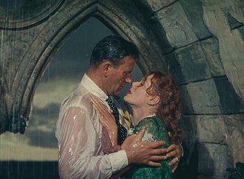 Movie still from “The Quiet Man” (1952), directed by John Ford – A man and a woman kissing in front of an archway; Medium shot, Low angle