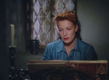 Movie still from “The Quiet Man” (1952), directed by John Ford – A woman sitting in front of an open book; Medium shot, High angle