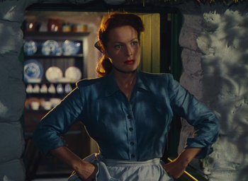 Movie still from “The Quiet Man” (1952), directed by John Ford – A woman standing in a room holding her hands on her hips; Medium shot, Low angle