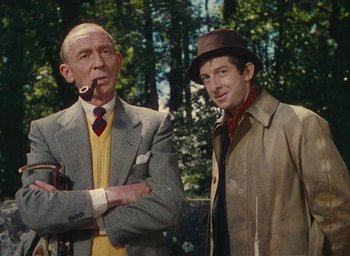 Movie still from “The Quiet Man” (1952), directed by John Ford – Two men standing next to each other in front of a forest; Medium shot, Low angle