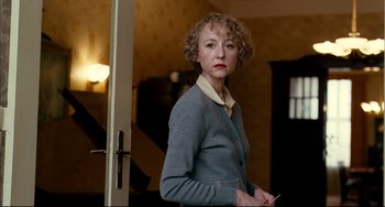 Movie still from “The Reader” (2008), directed by Stephen Daldry – A woman standing in a room holding a pen; Close Up shot, Over the shoulder angle