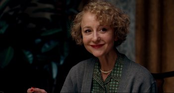A person with curly hair wearing a necklace