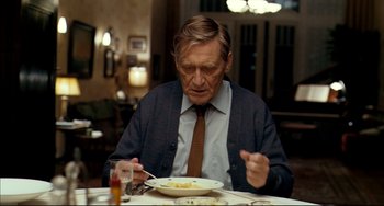 Movie still from “The Reader” (2008), directed by Stephen Daldry – An older man sitting at a table with a plate of food in front of him; Medium shot, Low angle