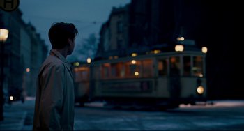 Movie still from “The Reader” (2008), directed by Stephen Daldry – A man standing in front of a train on a street; Medium shot, Low angle