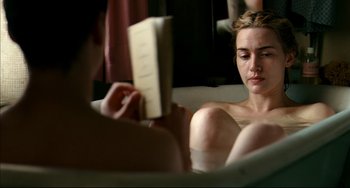 Movie still from “The Reader” (2008), directed by Stephen Daldry – A woman sitting on a couch reading a book; Medium shot, High angle