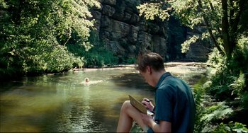 Movie still from “The Reader” (2008), directed by Stephen Daldry – A man sitting on the edge of a body of water; Wide shot, High angle