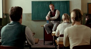 Movie still from “The Reader” (2008), directed by Stephen Daldry – A man sitting in front of a chalkboard in a classroom; Medium shot, Over the shoulder angle